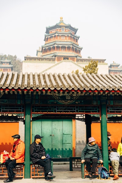 白天，人们站在绿色和棕色的木质建筑附近